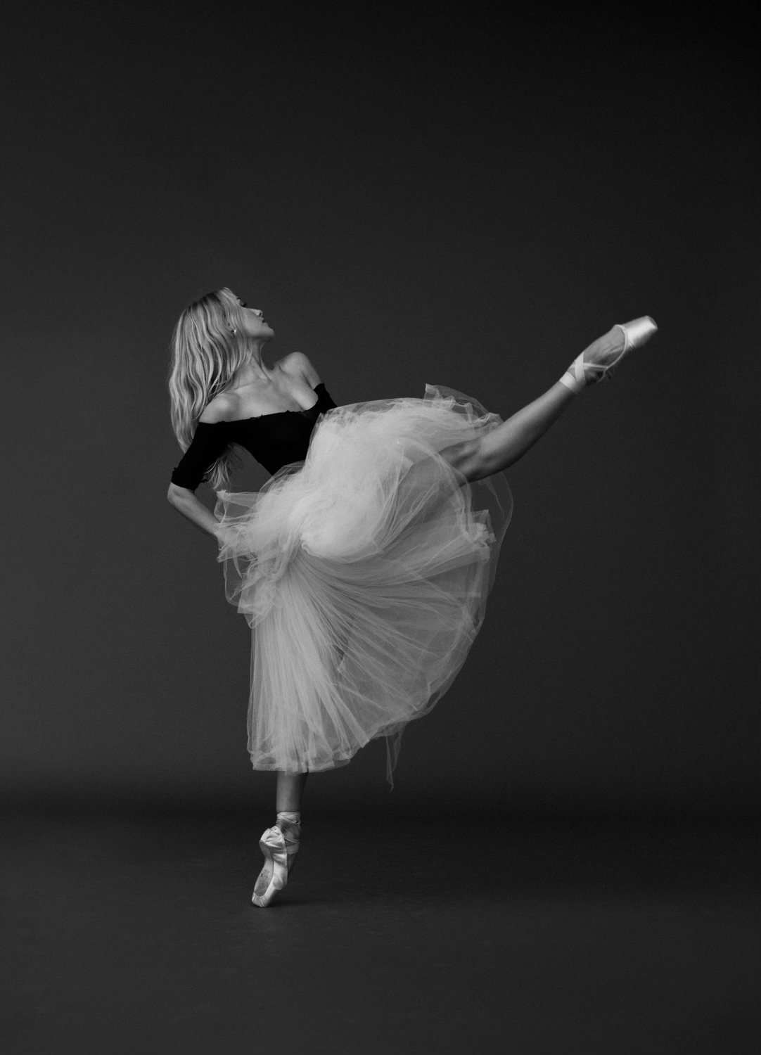 Solo ballerina silhouetted on a vast stage in a single spotlight